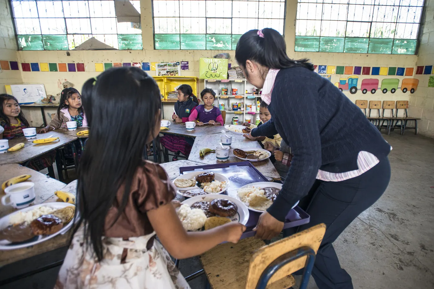 Una maestra acompaña a niñas y niños en el comedor de una escuela en Guatemala